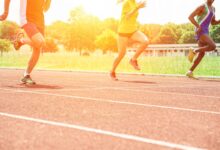 Athletes running on a synthetic athletics track at sunset