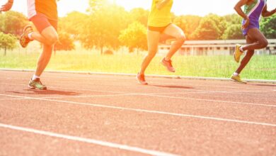 Athletes running on a synthetic athletics track at sunset