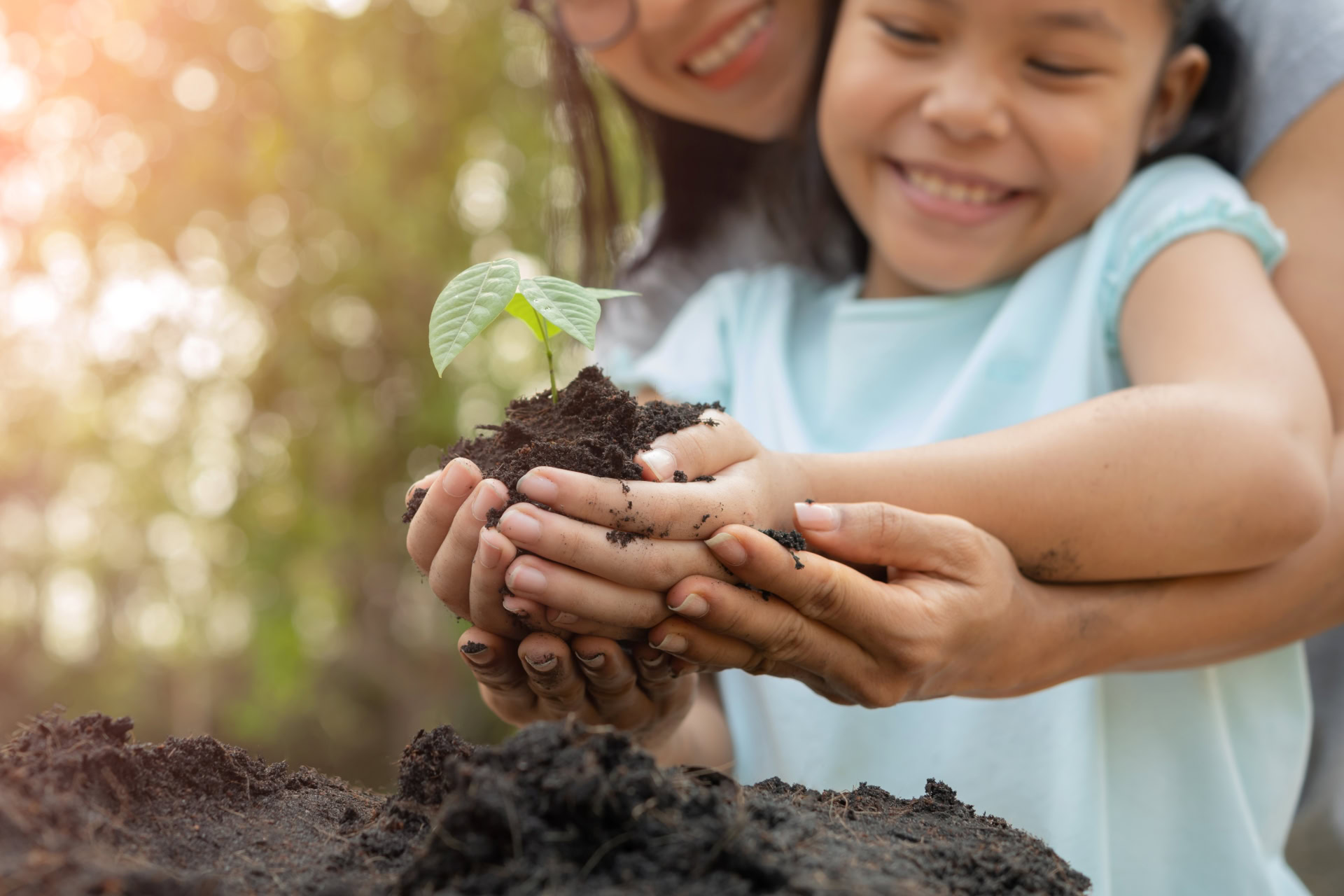 Mother and child planting a plant in the sun