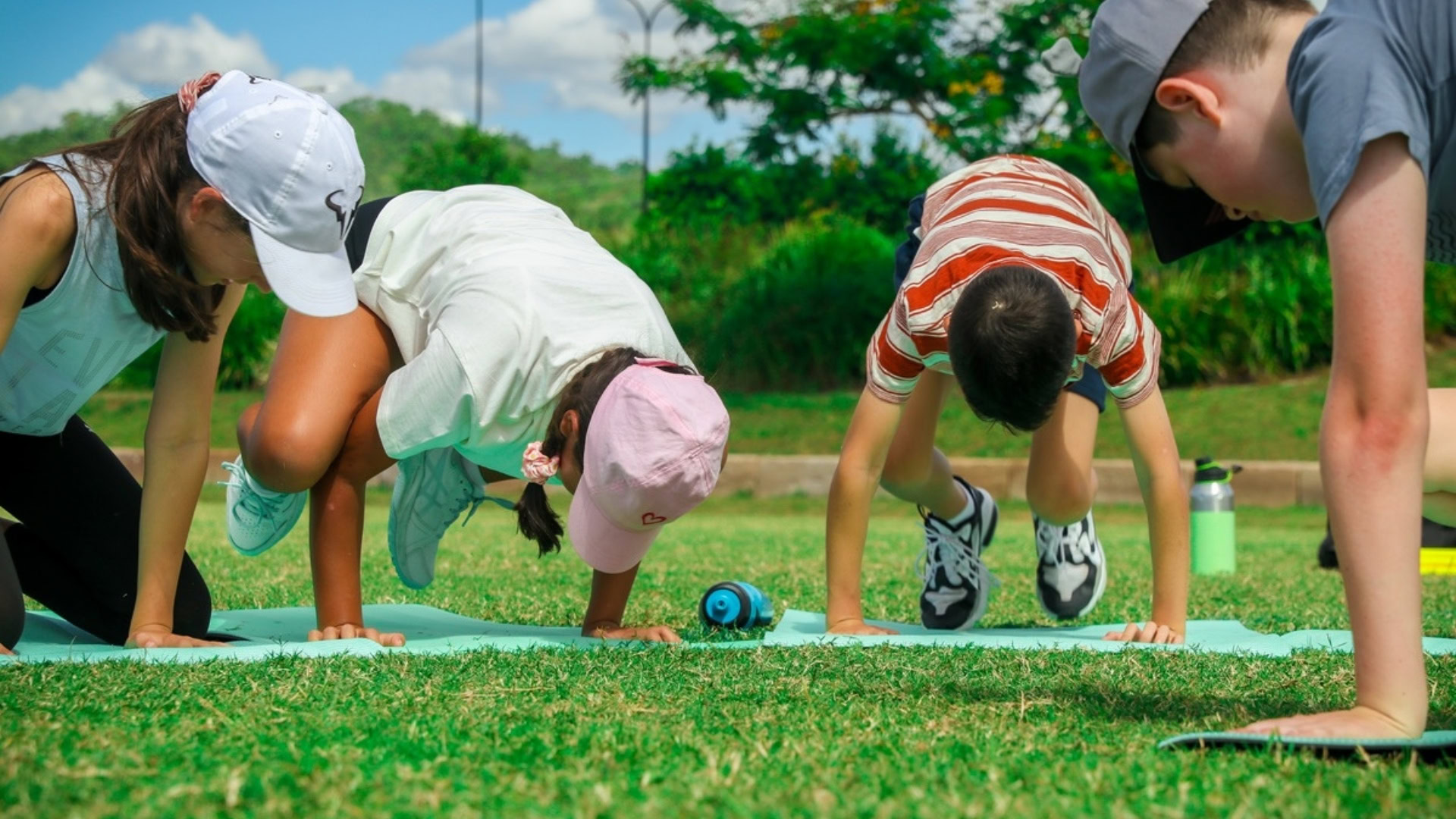 Kids doing push-up exercises outdoors in a park for fitness and health.